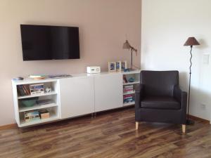 a living room with a chair and a television on a shelf at Sunny Apartment in Innsbruck