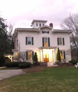 a white house with a front porch and a lawn at Antique Mansion B & B in Rutland
