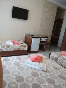 Habitación con 2 camas y mesa con TV. en Kontinental Guest House, en Anapa
