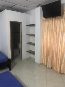 Habitación con cama y TV en la pared. en Cabaña La Fortaleza en Tolú