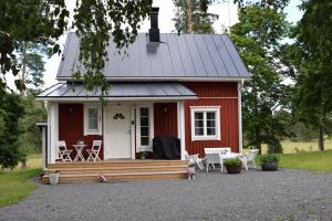 a red tiny house with a porch and chairs at Skogsbacka Torp in Tammisaari