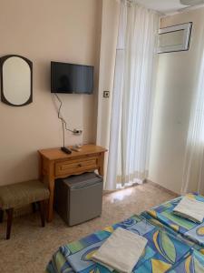 Dormitorio con cama, escritorio y TV en Rosi Guest House, en Lozenets