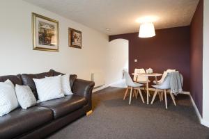 a living room with a leather couch and a table at Solihull 2 Bedroom Ground Floor Apartment with Parking - Available for Long Stays in Solihull