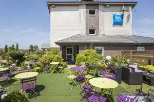 a patio with tables and chairs in front of a building at ibis budget Cabourg Dives sur Mer in Dives-sur-Mer