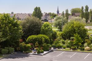 ogród z drzewami i krzakami oraz parking w obiekcie ibis budget Cabourg Dives sur Mer w mieście Dives-sur-Mer