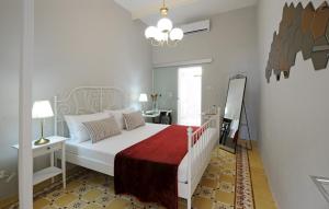 a bedroom with a white bed with a red blanket at Number 28 - The house with the blue door in Żebbuġ