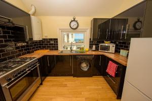 a kitchen with black cabinets and a clock on the wall at Cliff Top Apartment 3 Bedroom in Shanklin +19 photos