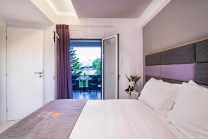 a bedroom with a large white bed and a balcony at Talos Luxury Suites in Kounoupidhianá +37 photos