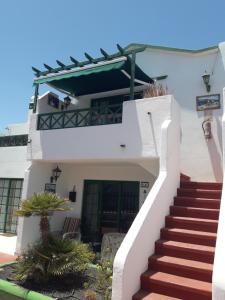 ein weißes Haus mit einer Treppe, die zur Eingangstür führt in der Unterkunft Vivienda Vacacional Casa Mar y Volcan Vista mar Piscina Playa 5 min Wifi in Puerto del Carmen