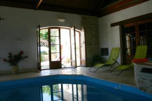 a room with a swimming pool and two green chairs at Hillside Park Dordogne in Saint-Lazare