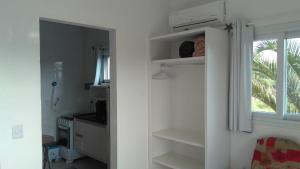 a kitchen with white shelves and a window at Pousada Morro do Rosa in Praia do Rosa