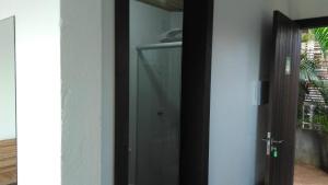 a glass door leading to a bathroom with a shower at Pousada Morro do Rosa in Praia do Rosa