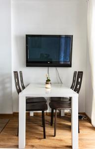 Biały stół z krzesłami i telewizor na ścianie w obiekcie Apartmán Reggie - Pec pod Sněžkou w mieście Pec pod Sněžkou