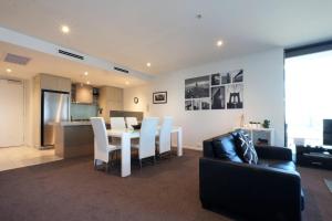 a living room with a table and chairs and a kitchen at ACD Apartments in Melbourne