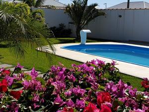una piscina en un patio con flores púrpuras en Maravilhosa Villa com Piscina, en Arraial do Cabo