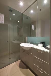 a bathroom with a sink and a shower and a mirror at ACD Apartments in Melbourne