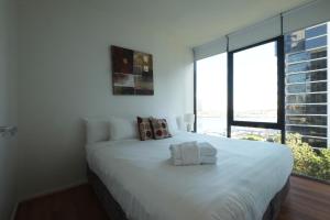 a large white bed in a room with a large window at ACD Apartments in Melbourne