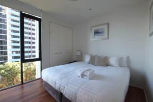 um quarto com uma cama branca e uma grande janela em ACD Apartments em Melbourne