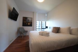 a bedroom with a bed with white sheets and a window at ACD Apartments in Melbourne