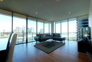 a living room with a couch and chairs and windows at ACD Apartments in Melbourne