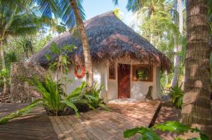 a small house with a thatched roof in the jungle at Ninamu Resort in Tikehau