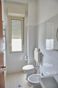 a white bathroom with a toilet and a window at Hotel Caesar Bed and Breakfast in Milano Marittima