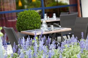 a table and chairs in a garden with purple flowers at Golden Tulip Paris CDG Airport – Villepinte in Roissy-en-France