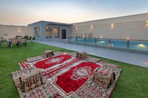 une terrasse avec un tapis rouge sur l'herbe à côté d'une piscine dans l'établissement The Corner Hotel Resorts - Riyadh, à Riyad