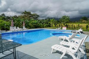 a swimming pool with white chairs and a bunch ofitures at Campos Arenal Hotel in Fortuna