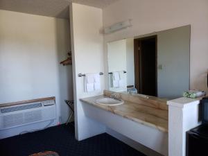 La salle de bains est pourvue d'un lavabo et d'un grand miroir. dans l'établissement Budget Inn, à Fallon