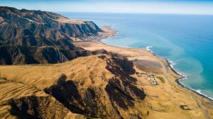 an aerial view of a mountain next to the ocean at Waimeha Camping Village in Ngawi