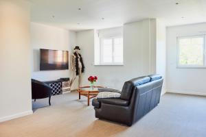 een woonkamer met een zwarte leren stoel en een tafel bij Le Rayon de Soleil - appartement 2 chambres 90m2 in Saint-Brieuc