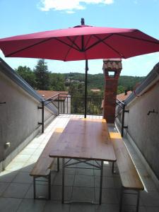 einen Picknicktisch mit einem roten Regenschirm auf dem Balkon in der Unterkunft Viki in Kastav