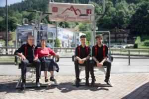 un grupo de personas sentadas en un banco del parque en Casteluce Hotel Funivie, en Pinzolo