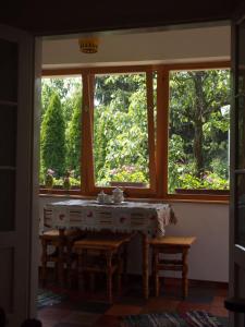 a dining room with a table and two windows at DéeL apartman in Nyíregyháza