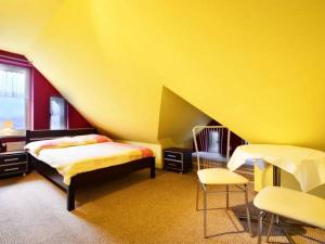 a yellow room with a bed and two chairs at Villa Mariano Michałowice in Piechowice