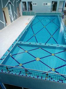 uma grande piscina com azulejos azuis no chão em Morakot Twin Chumphon em Chumphon