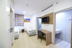 a bathroom with a sink, toilet and a television at HI - Eilat Hostel in Eilat
