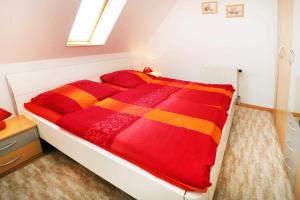 a bedroom with a bed with a red and orange blanket at Fewo Urlaubsidyll 2 in Ostseebad Karlshagen +4 photos