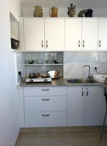 a kitchen with white cabinets and a sink at The Potter's House overlooking the Bay of Haifa in Haifa
