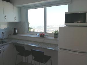 a kitchen with a counter with chairs and a window at The Potter's House overlooking the Bay of Haifa in Haifa