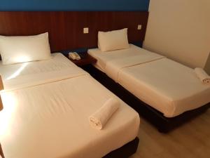 two beds in a hotel room with towels on them at Sun Inns Hotel @ Koi in Puchong