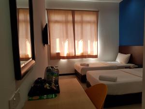 a hotel room with two beds and a window at Sun Inns Hotel @ Koi in Puchong