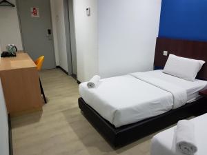 a hotel room with two beds and a desk and a room at Sun Inns Hotel @ Koi in Puchong