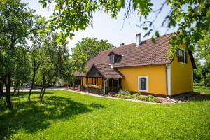 ein gelbes Haus auf einem grünen Rasen in der Unterkunft Tusculanum Panzió in Mindszentkálla