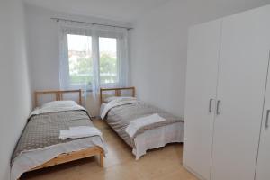 two beds in a white room with a window at Apartament Słoneczny 3 in Opole