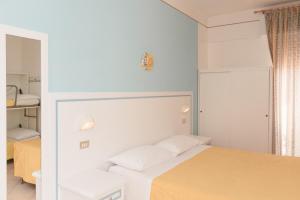 biała sypialnia z łóżkiem i lustrem w obiekcie Hotel Altair w mieście Misano Adriatico