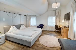 a bedroom with a large white bed and a desk at Hotel Steinerwirt1493 in Zell am See