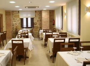 a restaurant with tables and chairs with white tablecloths at Hostal Restaurante La Muralla in Oña