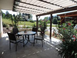 um pátio com uma mesa e cadeiras sob uma pérgola em Haus Assinger em Hermagor